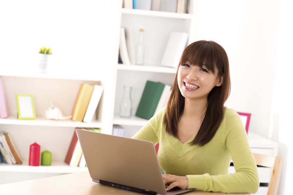 Happy Asian girl using laptop computer for online shopping at home