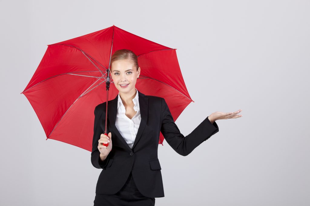 Businesswoman with red umbrella on gray background. Studio shot.
