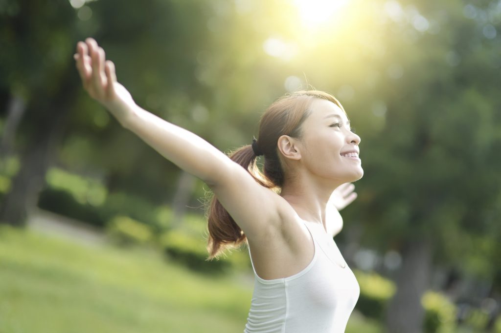 Carefree and free cheering woman in the park. girl raising her arms up smiling happy. asian beauty