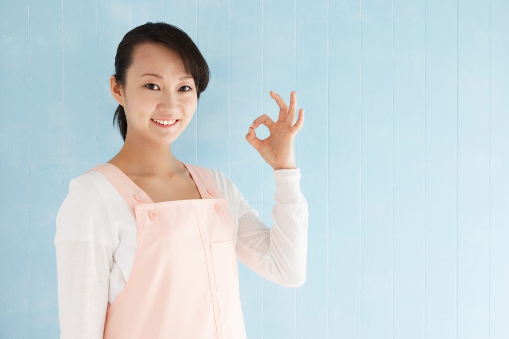 Beautiful young japanese woman to make a finger, blue tiled background with copy space.